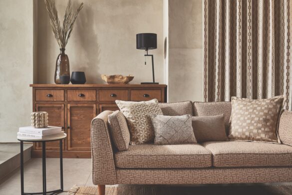 A low brown couch in the middle of a living room with a wooden sideboard and brown rug