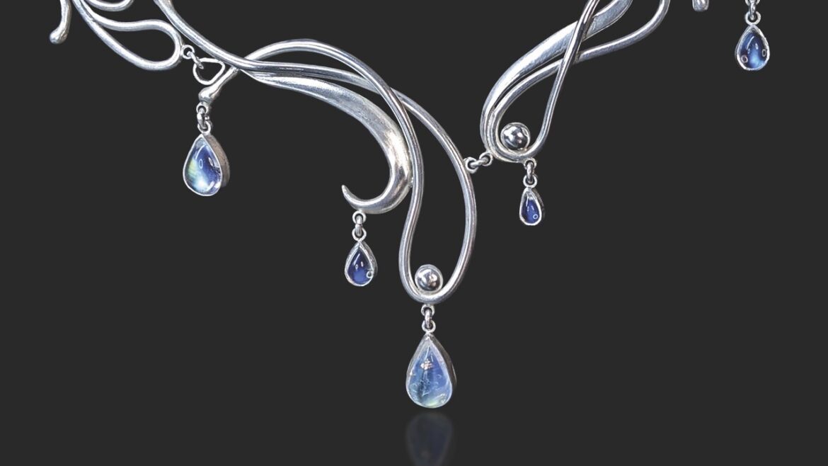 A curved silver necklace with blue inlays, against a black background