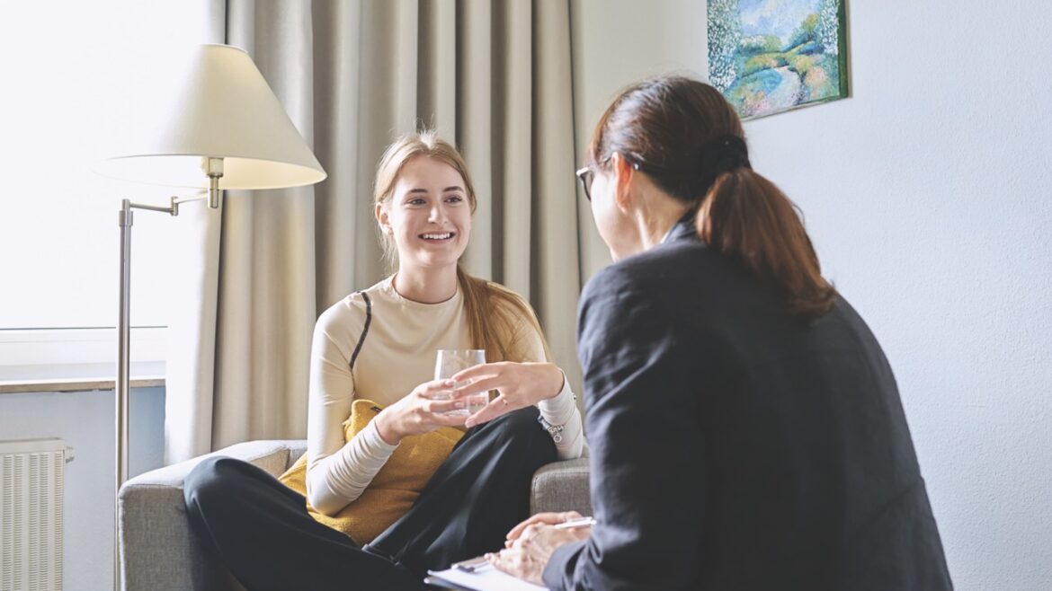 Two women having a chat in a therapy session. The young girl holds a cup of water
