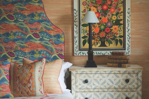 A bed with numerous pillows and a patterned dresser next to it. The bed has a bright headboard