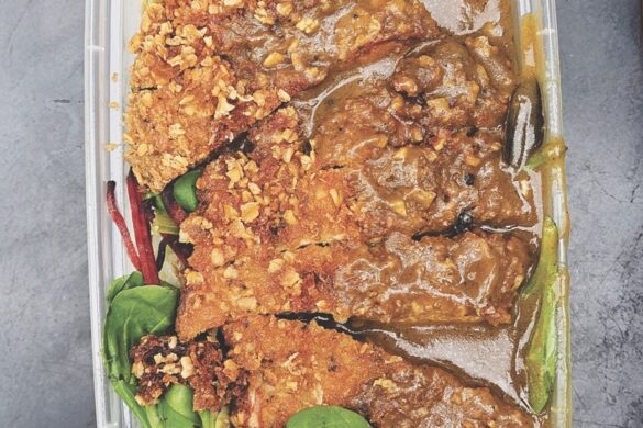 A red curry with salad around the outside in a takeaway box