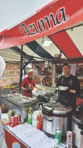 Two people working in a tented kitchen called Azuma, serving food