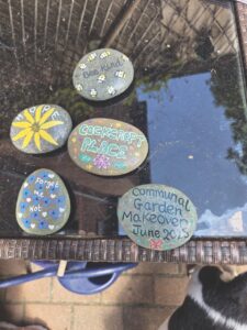 Smooth rocks with messages and art drawn onto them, sitting on a shiny black surface