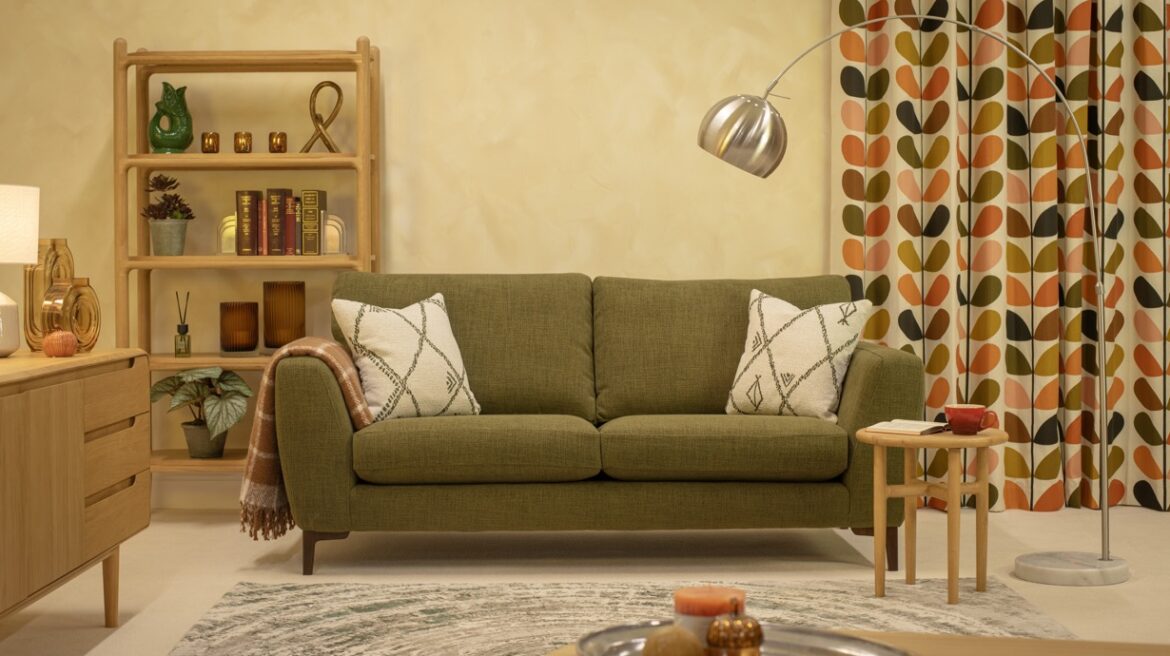 A comfy sofa in the middle of a living room with orange hues, a modern lamp and a wooden table