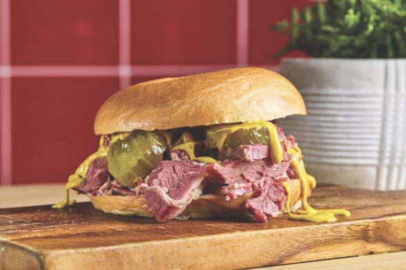 Big, bold sandwiches arrive on Green Street. Image by Charlie Bard Photography A burger packed with meat, sauce and pickles, sitting on a wooden chopping board in front of red tiles