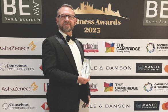 Hilton GM wins prestigious award A man holding a glass award and standing in a suit in front of a screen for the Business Awards 2025