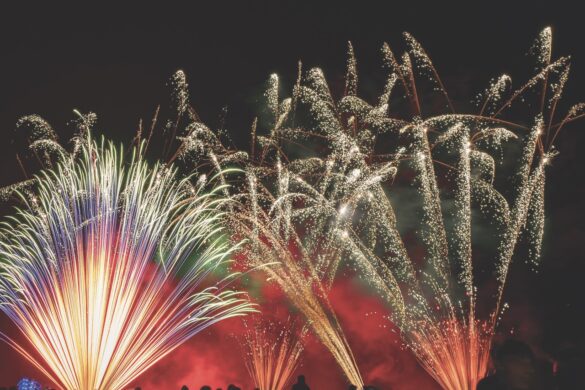 Fountain fireworks in red and yellow with a silhouetted crowd standing in front