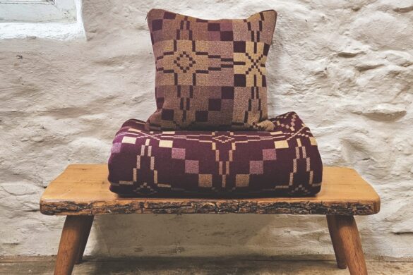 A burgundy blanket and pillow resting on a wooden stall near a textured wall