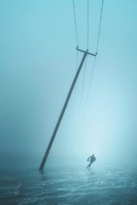 A person skating across an empty landscape with a mast leaning towards them in the frozen ice