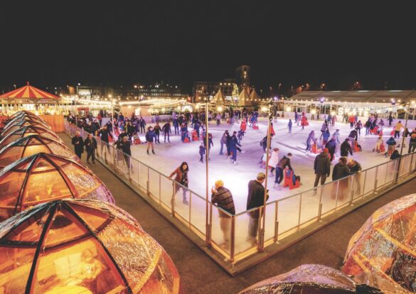 The edge of an ice skating rink filled with people at night