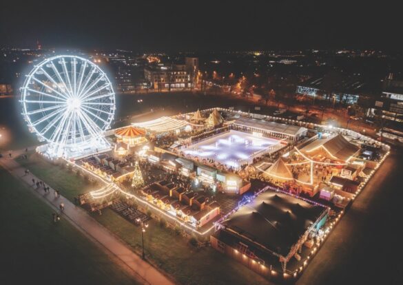 A top view of a winter festival with stalls, ice skating and a ferris wheel at night