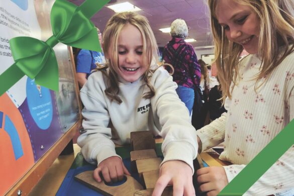 Two young girls building a puzzle in a public space