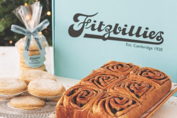 A plate of festive treats and Chelsea rolls on a table in front of a blue Fitzbillies bag