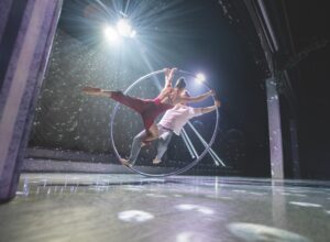 Two performers dancing together in a hoop on a dark and starry stage