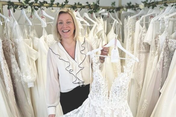A woman holding an elegant wedding dress and smiling