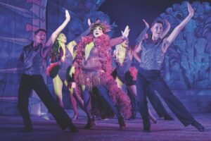 An ensemble performing with a dame on a purple stage