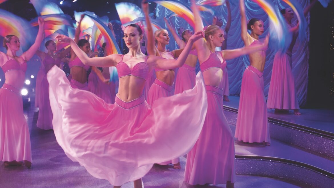 Dancers in pink outfits waving fabric on a stage
