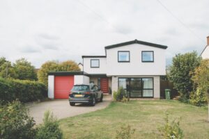 The driveway of a large house with a garage and a car parked outside