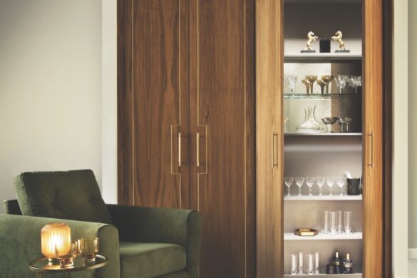 Add a touch of subtle sophistication with sleek cabinetry and metallic accents from Neatsmith A green armchair next to an open cupboard with a home bar inside