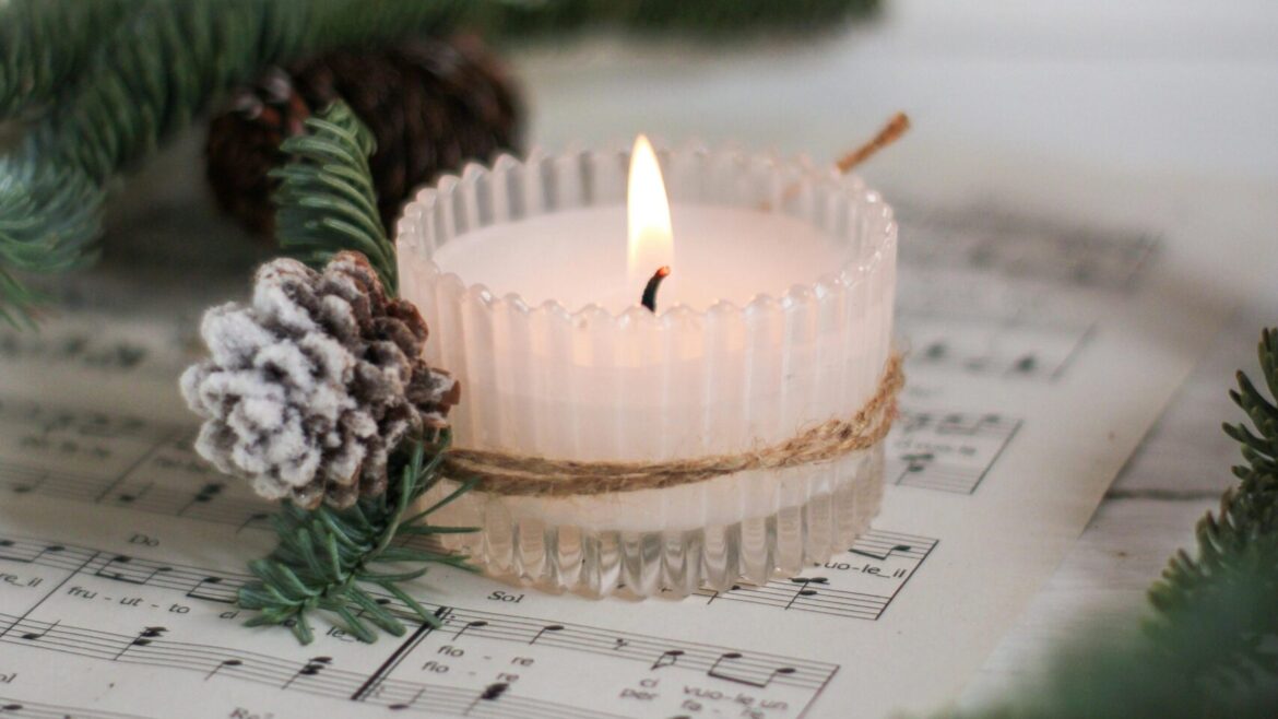 A tea light sitting on choir music with festive leaves next to it