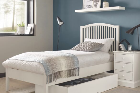 A single bed with a white frame and drawer underneath in a blue bedroom