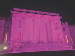 The front of a grand building glowing in purple light