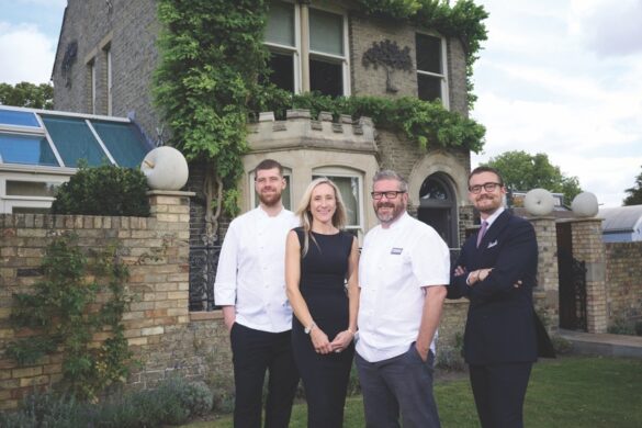 A group of four people stand outside an ornate home