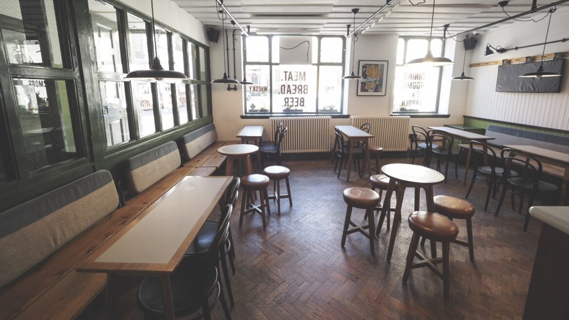 The interior of a restaurant with stools and wooden tables