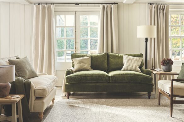 A living room with white floors and curtains and a green sofa