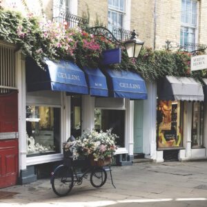 A bike with a basket of flowers parked outside a jewellery shop