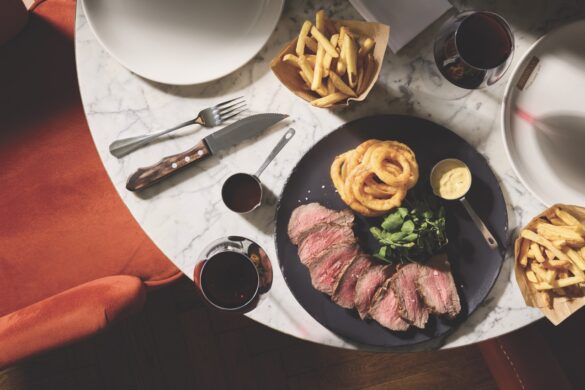 Top view of a plate of steak and onion rings on a round table
