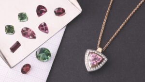 A purple necklace lying next to a collection of purple and green gems