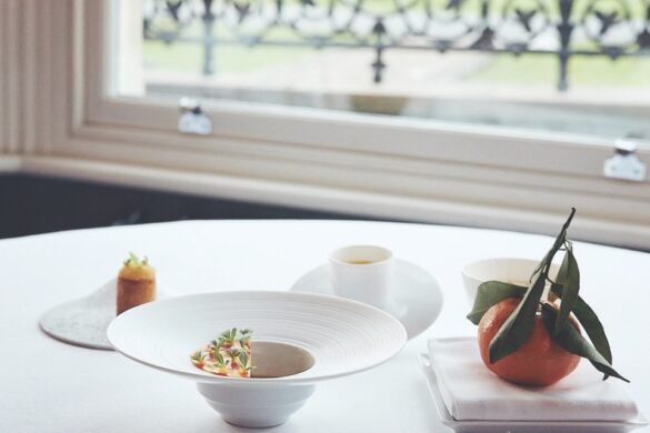 A round table by a window with numerous bowls and an orange nearby