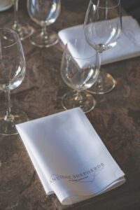 A napkin folded on a table next to empty wine glasses