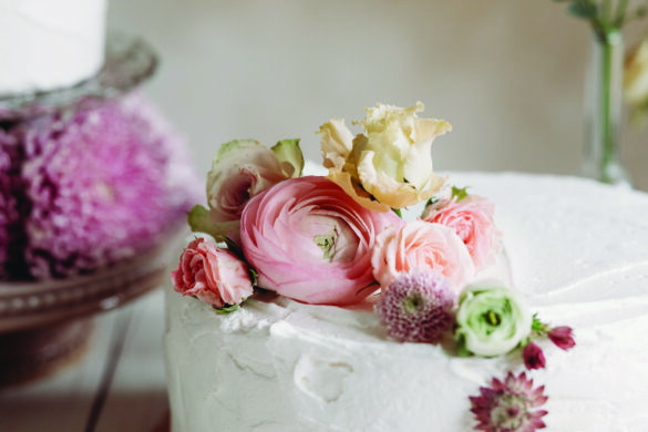 A white wedding cake with flowers spilling from the edge