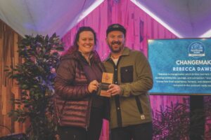 A man and woman holding an award in front of a pink curtain