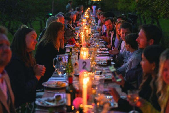 A long table placed outside and illuminated with candles and fairy lights