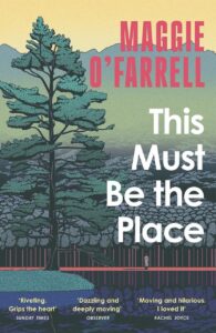 A book titled This Must Be The Place with a forest landscape on the cover