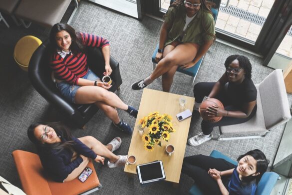 A top-view of a group of students looking up while sitting on chairs around a small coffee table