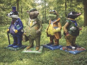 A line of animal sculptures wearing suits in a forest clearing
